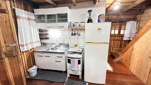 a kitchen with a white refrigerator and a stove at Chalé Xodó da Serra Urubici in Urubici