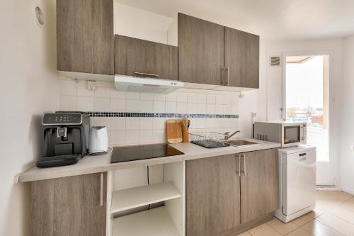 une cuisine avec des armoires en bois et un comptoir dans l'établissement Charmant 2 chbres Paris Stade de France avec Parking privatif, à Épinay-sur-Seine