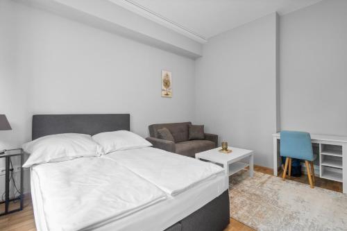 a white bedroom with a bed and a chair at Domloge Lofts & Apartments in Cologne