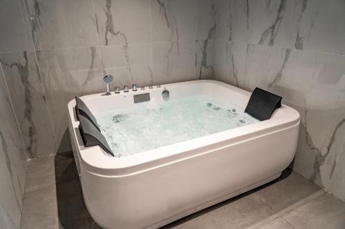 La salle de bains est pourvue d'une baignoire blanche et de murs en marbre. dans l'établissement Hafawah Resort, à Médine