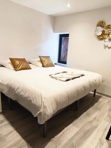 un lit avec des draps blancs et des oreillers dans une chambre dans l'établissement Duplex centre village et proche commodités, à Champagne-en-Valromey