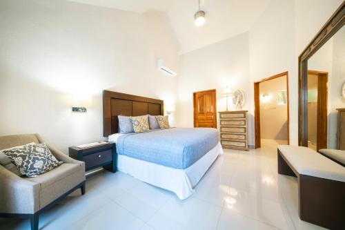 a bedroom with a bed and a couch and a chair at Luxury Villa 4BR with Private Pool - At Playacar ll - Villa Perla 15 in Playa del Carmen