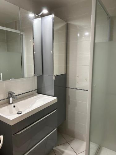 une salle de bain blanche avec un lavabo et une douche dans l'établissement T2 Les pieds dans l'eau, accès direct plage, à Valras-Plage