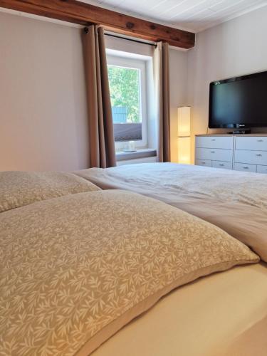 a bedroom with a large bed with a flat screen tv at Ferienwohnung Hein sien Huus Rodenäs Nordfriesland in Rodenäs