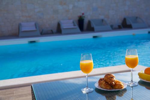 two glasses of orange juice and pastries on a table by a pool at Banić Apartments with pool in Biograd na Moru