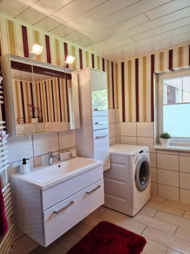 a bathroom with a sink and a washing machine at Ferienwohnung Hein sien Huus Rodenäs Nordfriesland in Rodenäs