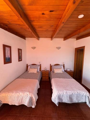 two beds in a room with wooden ceilings at Apartamento junto al mar El Roque in Santa Cruz de Tenerife
