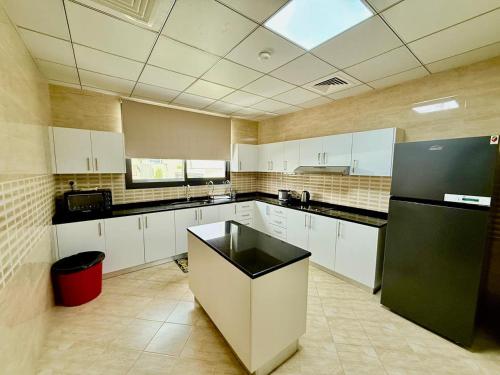 a kitchen with white cabinets and a black refrigerator at Lux 4 with Assistance room with Pool and Sea View in Fujairah