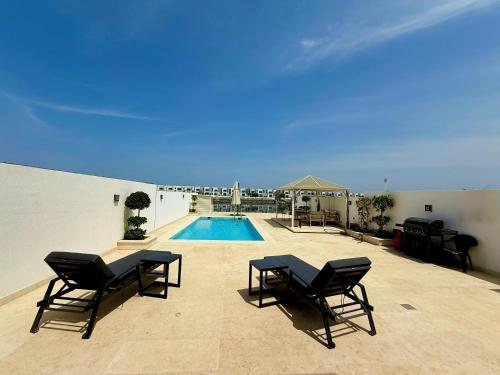 a patio with chairs and a swimming pool at Lux 4 with Assistance room with Pool and Sea View in Fujairah