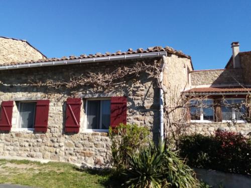 une ancienne maison en pierre avec des fenêtres rouges à volets dans l'établissement Gîte Au Bonheur des Hôtes en Auvergne, à Égliseneuve-près-Billom