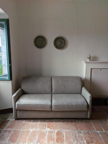a couch sitting in a corner of a room at Giardino in piazza, casa in pietra a San Leo in San Leo