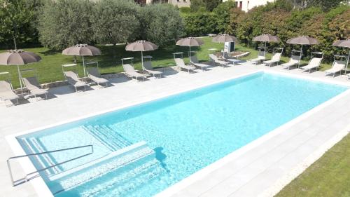 a large swimming pool with chairs and umbrellas at Villa Trieste M in Asolo