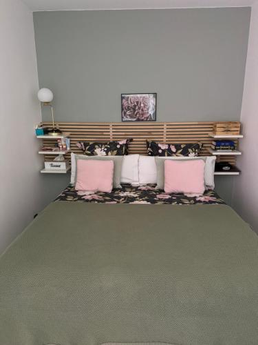 une chambre avec un grand lit avec des oreillers roses dans l'établissement Belle appartement calme proche aéroport 80m2, à Vitrolles