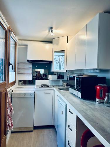 une cuisine avec des armoires blanches et des appareils électroménagers blancs dans l'établissement Studio proche Tram T2, à Courbevoie