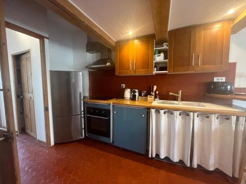 une cuisine avec des armoires en bois et un réfrigérateur en acier inoxydable dans l'établissement Le Duplex des Papes, à Avignon