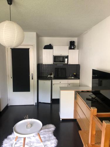 une cuisine avec des armoires blanches et une table blanche dans l'établissement Studio 4 pers rénové, vue pistes - Les Orres 1650, à La Celle-sous-Gouzon