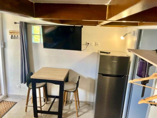 a small kitchen with a table and a refrigerator at Studio cosy équipé à 5min de la plage in Vieux-Habitants