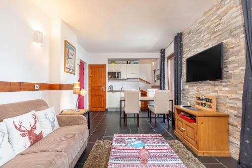 a living room with a couch and a tv at Les Aiguilles de Warens - Combloux in Combloux