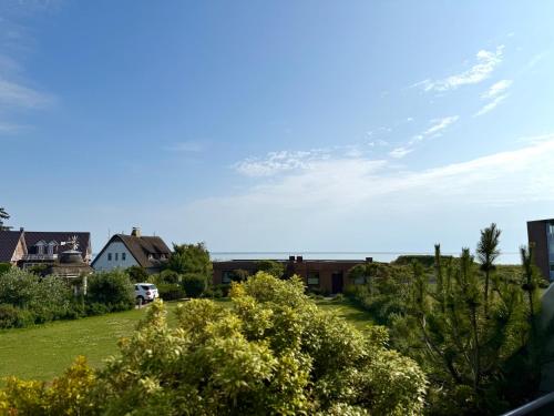 Blick auf einen Garten mit einem Haus und das Meer in der Unterkunft Halligblick Whg 11 - b70828 in Wyk auf Föhr