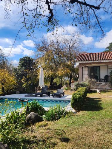 a backyard with a pool with two chairs and an umbrella at Apart exclusivo piscina BIA Encanto serrano Stay&Flow in Río Ceballos