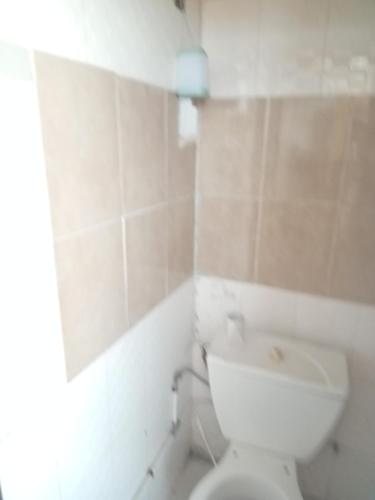 un bagno con un water bianco e uno specchio di Chris a Abidjan