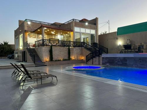 a house with a swimming pool in front of a building at The Royal Chalet in Ath Thukhaynāt