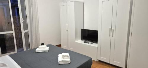 una camera con letto, TV e armadietto bianco di Door to 5 terre a La Spezia