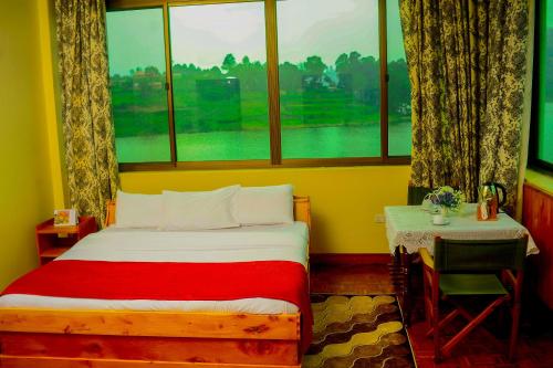 a bedroom with a bed and a window and a desk at Bunyonyi Safaris Resort in Kabale