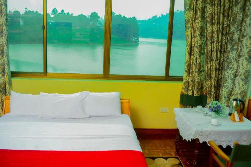 a bed in a room with a large window at Bunyonyi Safaris Resort in Kabale