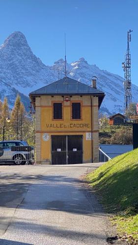 a yellow building with a car parked in front of it at Il Cadorino in Valle di Cadore