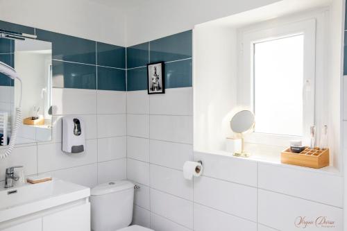a white bathroom with a toilet and a window at L Escale in Ports