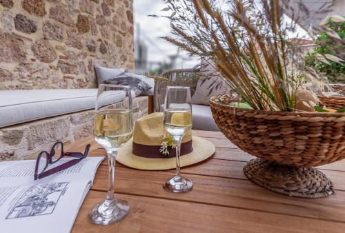 two glasses of wine and a hat on a wooden table at ACRO Upscale Residences in Kórinthos