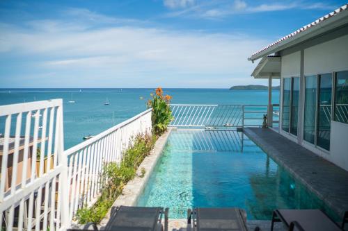 a swimming pool on the side of a house overlooking the ocean at mona seaview pool villa beach front AoYon Beach in Ban Ao Makham