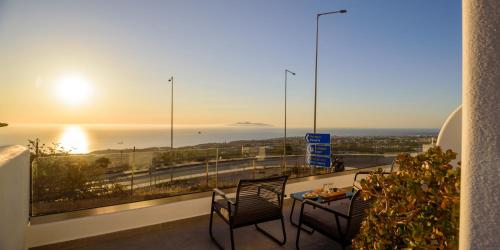 a balcony with two chairs and a table and the sunset at Casa della Liberta in Firostefani