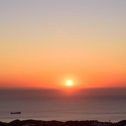 a sunset over the ocean with a boat in the water at Casa della Liberta in Firostefani