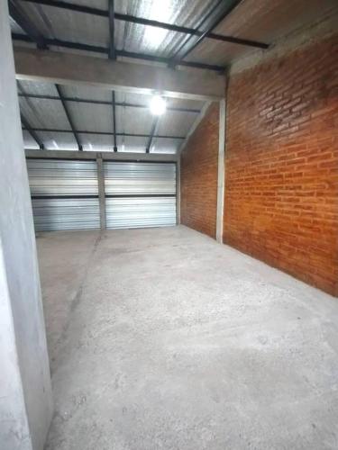 an empty garage with a garage door and a brick wall at Las Dos Tinajas in La Punta