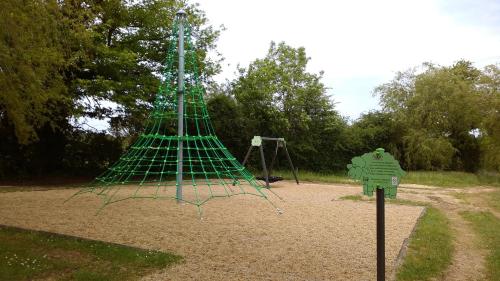 a playground with a green structure in a park at Pescalis Résidence Les Maisons du Lac in Moncoutant