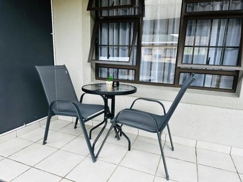 two chairs and a table on a balcony with a window at Sweet Daisies Apartment in Mbabane