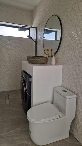 a bathroom with a white toilet and a mirror at Luxury manao poolvilla with seaview Koh Lanta in Ko Lanta