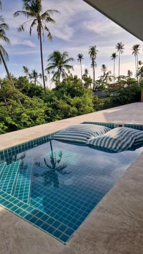 a blue tile swimming pool with palm trees in the background at Luxury manao poolvilla with seaview Koh Lanta in Ko Lanta