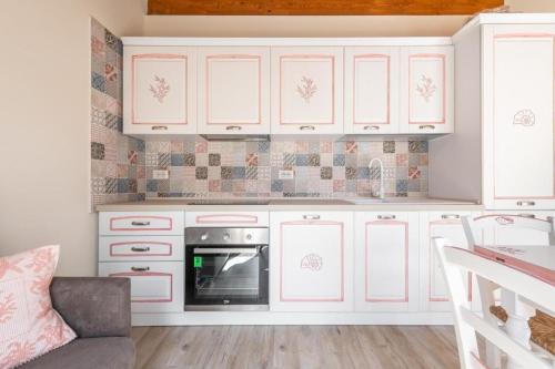 a kitchen with white cabinets and a stove at Su Mari in Villasimius