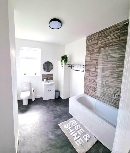 a bathroom with a tub and a toilet and a sink at Stunning 2 Bed House, Cleethorpes - Contractors Welcome! in Cleethorpes