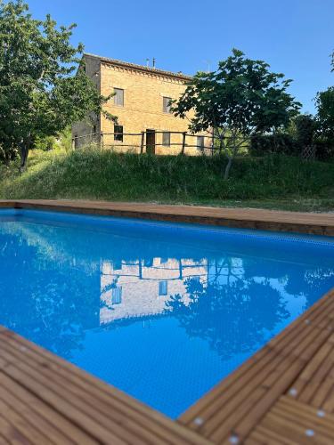 a blue swimming pool with a house in the background at Tenuta Gran Bosco in Loro Piceno