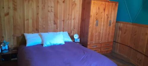 a bedroom with a purple bed and wooden walls at CABAÑA DOMO EN VILLARICA TERRADOMOS AFUNALHUe in Nalcahue