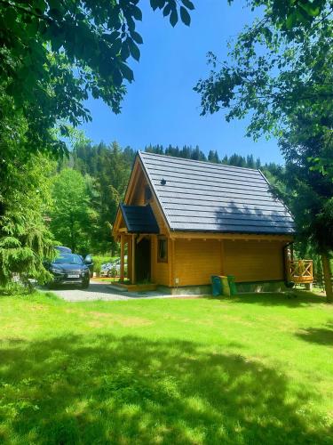 a log cabin with a car parked in a yard at DOMKI JANOSIK - Janosik Premium in Łopuszna