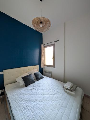 une chambre avec un grand lit avec un mur bleu dans l'établissement Uzès centre à 2 min - piscine - clim - parking, à Uzès