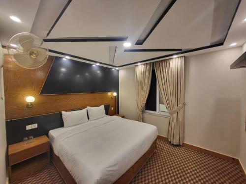 a bedroom with a white bed and a fan at Dolphin Lodge in Murree