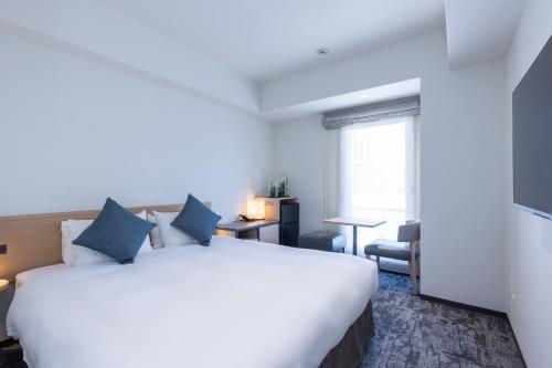 une chambre d'hôtel avec un grand lit blanc et une fenêtre dans l'établissement Tokyu Stay Osaka Hommachi, à Osaka