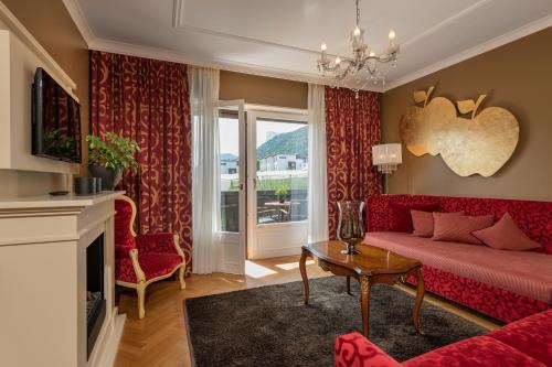 a living room with a red couch and a fireplace at Tirolensis - Luxury All Inclusive in Tesimo