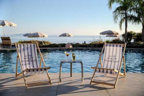 two chairs and a table next to a pool at Hôtel La Villa Douce in Rayol-Canadel-sur-Mer